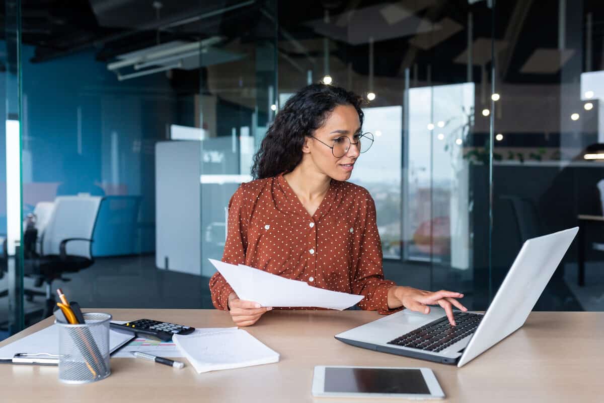Young happy and successful businesswoman in glasses working with documents inside office.